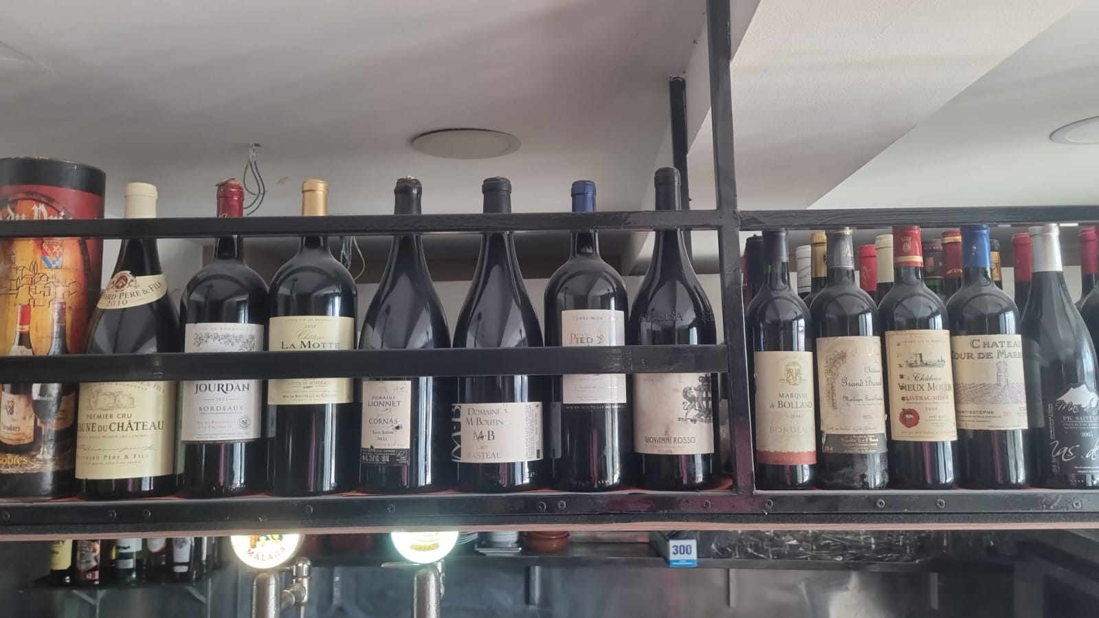 Shelf lined with French Bordeaux wine bottles behind the bar at La Casa Francesa